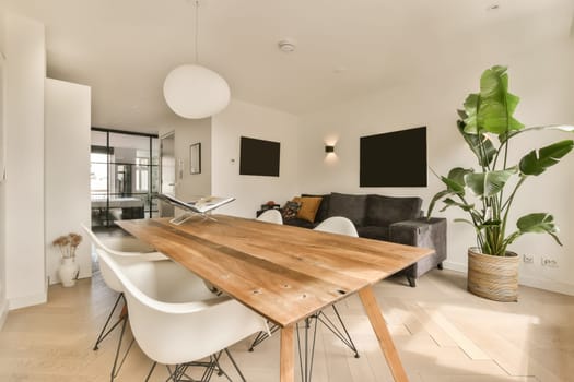 a dining room with white chairs and a wooden table in the center of the room there is a tv on the wall