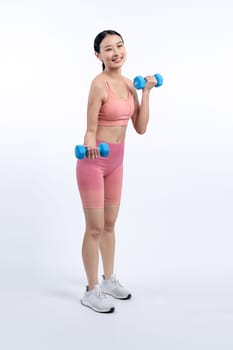 Vigorous energetic woman doing dumbbell weight lifting exercise on isolated background. Young athletic asian woman strength and endurance training session as body workout routine.