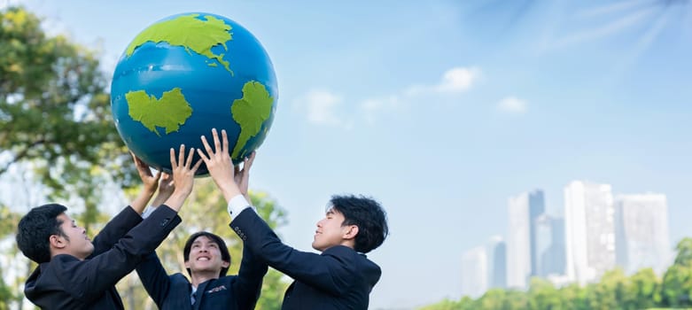 Earth day concept with big Earth globe held by group of asian business people team promoting environmental awareness with environmentally sustainability and ESG principle for brighter future. Gyre