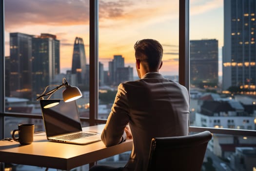 A man in a business suit works at a laptop in a modern office with large panoramic windows.