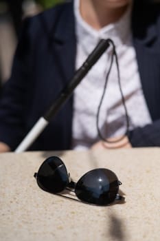 A blind woman in a business suit is sitting in an outdoor cafe