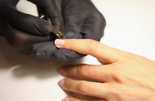 Gloved manicurist uses nippers to cut cuticles on nails. Manicure and pedicure tools concept.