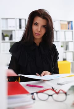 Beautiful smiling brunette woman sit at table hold in arm papers portrait colleagues in background. White collar worker at workspace officer highly pay smart serious headhunter offer