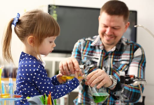 Man and little girl play with colourful liquids portrait. Young team clean research equipment colour reagent food additions flavor activity flavour concept