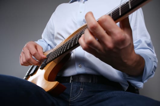 Male arms holding and playing classic shape wooden electric guitar closeup. Six stringed learning musical school education art leisure electrical vintage stage shop having fun enjoying hobby concept