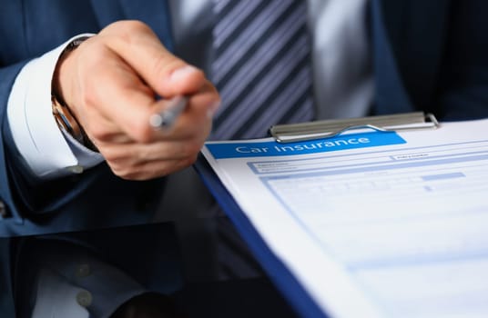Male arm in suit offer contract form on clipboard pad and silver pen to sign closeup. Strike a bargain for profit, white collar motivation union decision corporate sale insurance agent concept