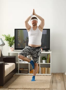 A young man practicing yoga and Pilates at home dreams of an excellent figure being restored. After an intense load for the body to lose weight.