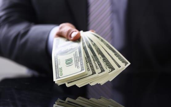 Man in suit and tie hold in arm pack of hundred dollar bills closeup. Stock market exchange earn pile rich present gift employer prepayment service gratitude concept