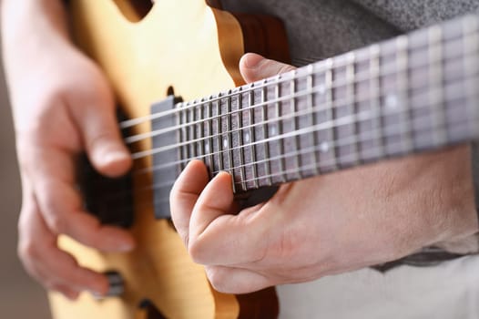 Male arms holding and playing classic shape wooden electric guitar closeup. Six stringed learning musical school education art leisure electrical vintage stage shop having fun enjoying hobby concept