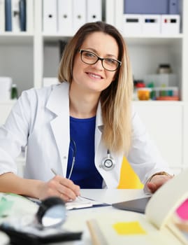 Beautiful smiling female doctor sit at workplace. Physical and disease prevention patient aid exam visit 911 ward round prescribe remedy healthy lifestyle consultant profession concept