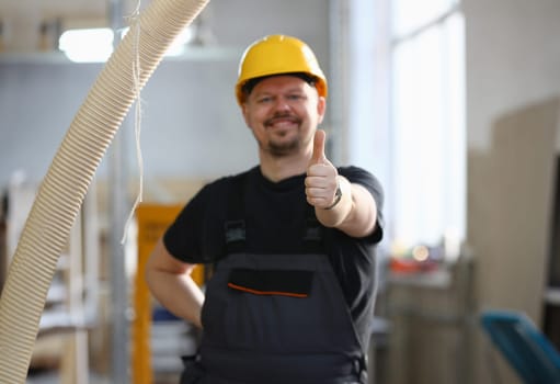 Smiling worker in yellow helmet show confirm sign with thumb up at arm portrait. Manual job DIY inspiration joinery startup idea fix shop hard hat industrial education profession career concept