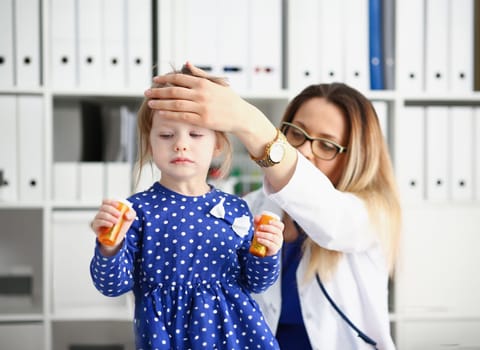At doctor reception little child. The pediatrician measures temperature with an palm of hand to the forehead rise high very quickly baby