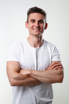 Fitness man portrait cute in a white tank top on a gray background smiling and looking at the camera fashion industry model