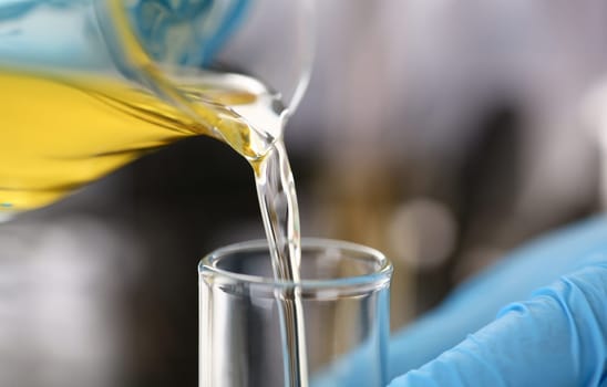 Male hands in protective gloves hold test tube in hands produces chemistry test of motor oil automatic gearbox and hydraulic booster