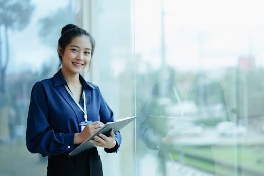 Portrait of a woman business owner showing a happy smiling face as he has successfully invested her business using financial budget documents at work.