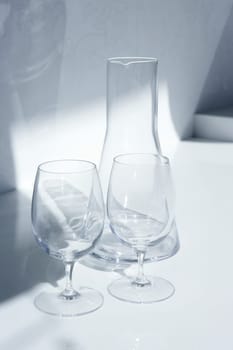 Water glass and bottle with transparent shadows in white kitchen