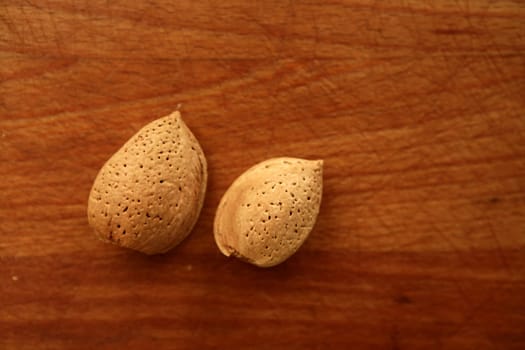 Two almond nuts on a golden wood aged table