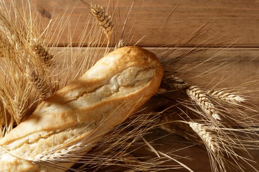 Bread over wooden table with ear wheat spikes