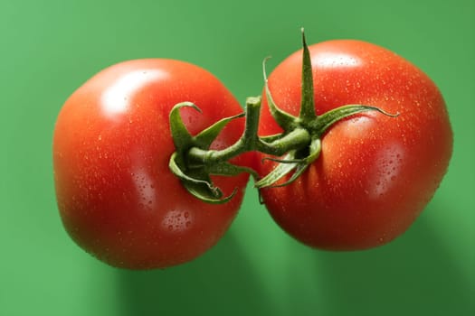 Red wet tomato macro over green background at studio