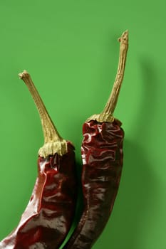 Two dried pepper, chili , over vivid studio green background