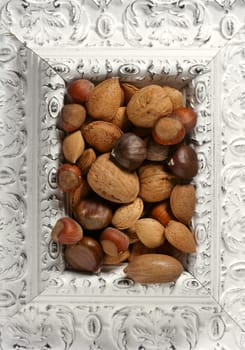 wooden decorated classic white frame, varied nuts inside