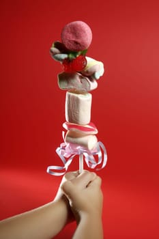 Candy colorful lolipop on child hand over red background