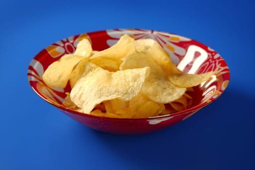 Potato fried chips on red plate over blue background