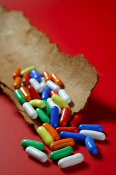 Colorful candy sweets in a wooden bark over red background