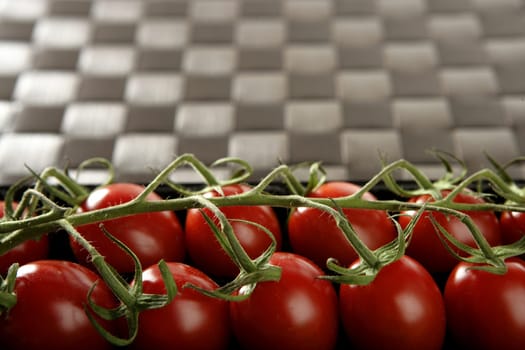 Red tomatoes branch un a black plastic box over brown tablecloth