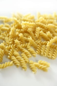 Italian spiral pasta texture with selective focus, white studio background