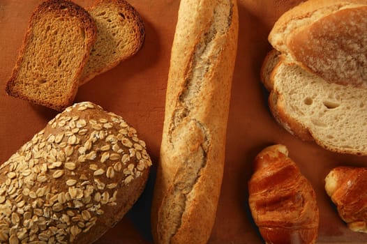 Varied bread styles still over warm clay background
