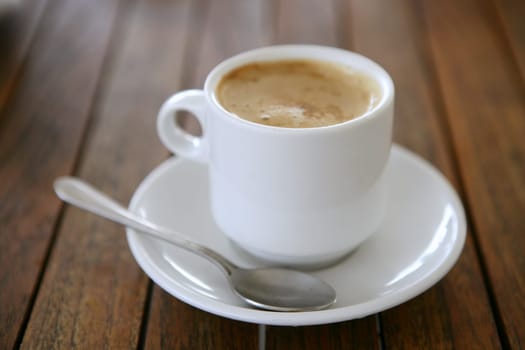 Coffe with milk white cup over teak wooden background
