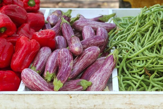 eggplant red pepper green beans on market store texture background