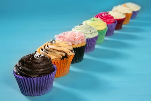 Cupcakes colorful cream muffin arrangement in a row line on turquoise