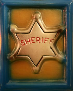 golden plastic sheriff toy star in a blue frame