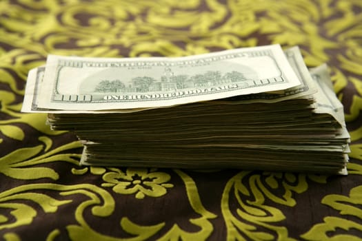 Many dollar notes over brown and yellow tablecloth, US currency