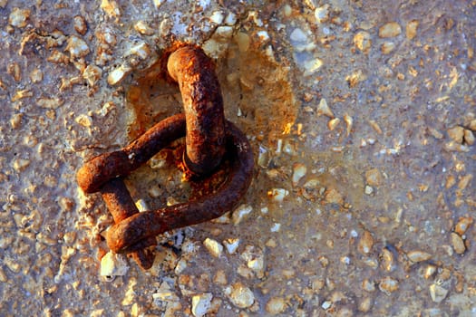 old rusted shackle on the harbor concrete stones, golden sunset light