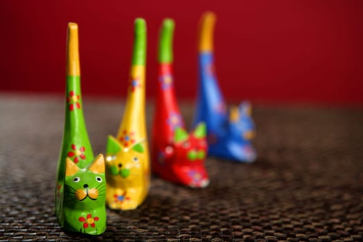four handcraft cats in colors still over brown tablecloth
