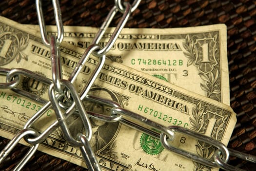 One Dollar notes in chains studio shot over brown background