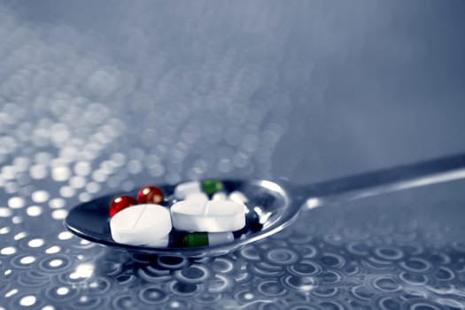 Silver spoon full of medicine pills over holographic background