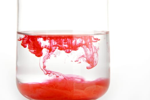 Color pigments into the water making clouds, over white background