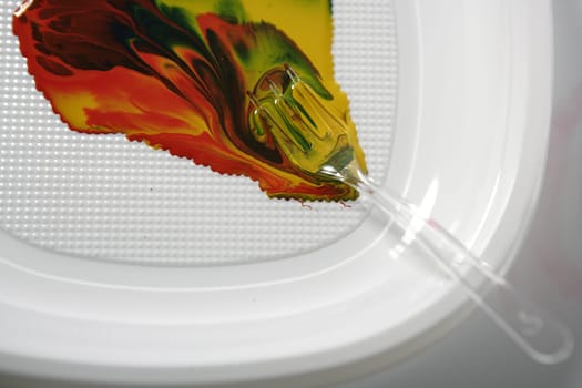 Paint colorful mix with a plastic fork, in white dish