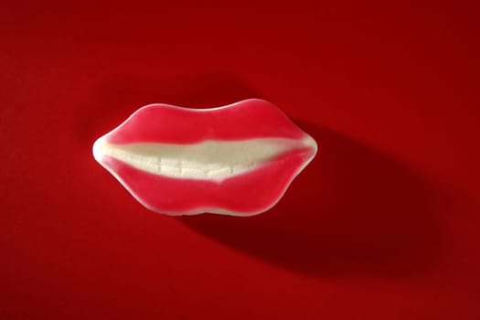 Candy gum jelly toy lips over red studio background
