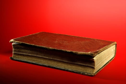 Old aged classic book close up over red background