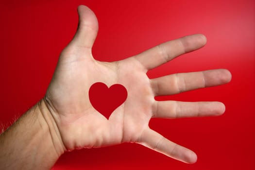 Red heart shape drawed on a male human hand, red backround
