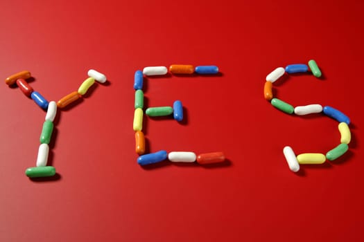 Candy colorful sweets with letter shapes spelling the word YES, over red