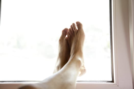 Human feet on the white window, relax metaphor