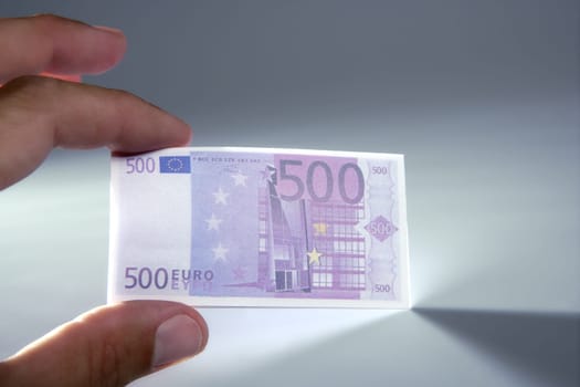 Human fingers holding little euro notes currency over gray background
