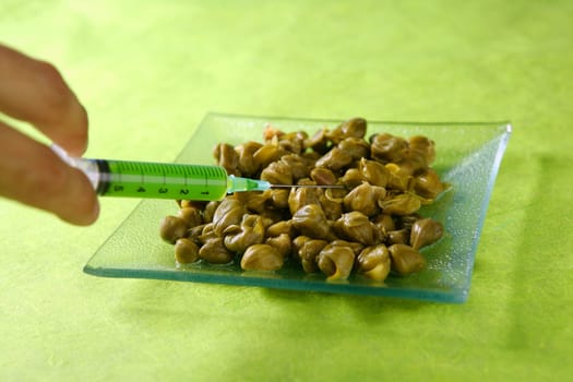 Food research metaphor with green syringe and tapera dish