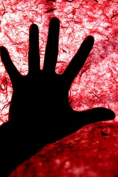Backlight of human hand over red textured surface, bloody
